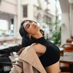 This shot captures a feeling of freedom and relaxation. The simple, well-fitting black crop top is a wardrobe staple that can be dressed up or down.