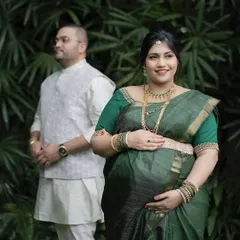 A classic portrait of the mother-to-be during her outdoor maternity shoot, with her partner in the background. This style combines a formal portrait with a natural, candid feel.