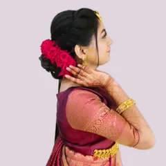 A sophisticated side-profile view of a sleek bun adorned with vibrant red roses. This hairstyle is a bold and romantic choice, perfect for making a statement at a reception or engagement party.