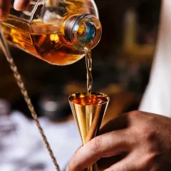It all starts with the right technique. Here, you see the precise pour of a quality whiskey into a golden jigger, showing the professional standards I bring to every single drink we make at your event.