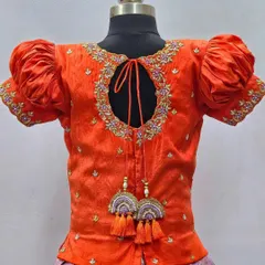 A detailed view of the back of an orange blouse, showing the keyhole design and the intricate embroidery around the neckline.