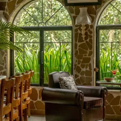 This seating area at Echoes captures the essence of Himalayan serenity. The combination of a comfortable leather armchair, rustic stone walls, and large arched windows framing the outdoors offers a tranquil escape from the city.