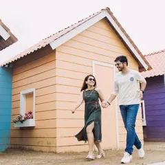 A fun, candid shot of the couple walking past colorful beach-style huts. This set is great for capturing a playful, holiday vibe in your pre-wedding photos.