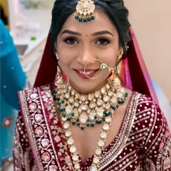 A smiling bride looking absolutely radiant in her maroon velvet lehenga. The makeup features a classic winged liner and a smile that lights up the room.