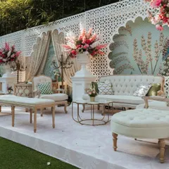 A luxurious seating area with a pastel blue peacock-themed wallpaper backdrop. The design combines classic furniture with vibrant floral arrangements and elegant candelabras for a touch of royalty.