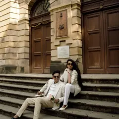 A stylish, modern pre-wedding shoot in Mumbai. The couple's coordinated white outfits look sharp against the classic stone architecture.