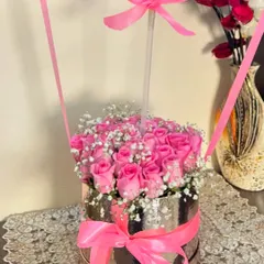 The base of our hot air balloon arrangement, showcasing a dense cluster of beautiful pink roses and delicate baby's breath nestled in a reflective silver box with a matching pink bow.