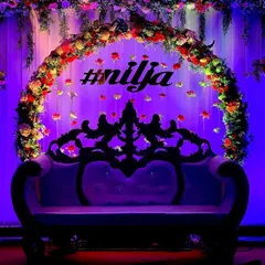 We created this dramatic and elegant seating area for a baby shower. A lush floral arch frames a classic carved sofa, all illuminated by deep purple uplighting to create a rich and luxurious atmosphere for the parents-to-be.