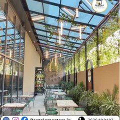 This glass roof pergola transforms a cafe's outdoor seating area into a lush, all-weather conservatory. The transparent roof protects patrons from the elements while allowing light to nourish the abundant greenery.