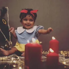 A little Snow White celebrating the season. Using warm candles and fairy lights, I can create a cozy and magical atmosphere for a Christmas-themed photoshoot right in your living room.