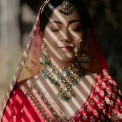 An artistic bridal portrait, with shadows from a window creating beautiful stripes of light across the bride's face, highlighting her features and jewelry.