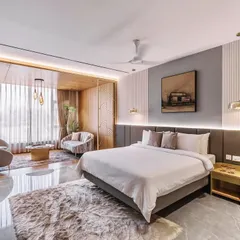 This hotel room interior is an exercise in refined comfort. We used a combination of fluted wall panels, warm wood, and custom art deco-inspired screens to create a distinct seating area within the room, making the space feel more like a personal suite.