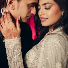 An intimate close-up that focuses on the bride's gentle touch and the couple's serene expressions. The intricate henna and sparkling engagement ring are beautiful details that enhance this romantic portrait.