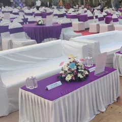 For larger corporate events, offering a variety of seating is important. Here you can see a mix of comfortable lounge sofas and traditional round tables, all cohesive with the event's purple and white color scheme.