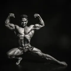 The same pose in black and white, which emphasizes the shadows and muscular detail. It highlights the separation in the quads, biceps, and abdominals that comes from low body fat.