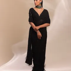 A full-length shot showcasing a modern interpretation of classic elegance. I styled this black sequined saree with a statement emerald green choker, adding a pop of color and a touch of contemporary glamour to the timeless silhouette.