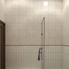 A minimalist bathroom design using two types of tiles. The vertically laid subway tiles on the lower half and the larger square tiles above are separated by a clean black line, creating a simple yet effective design.