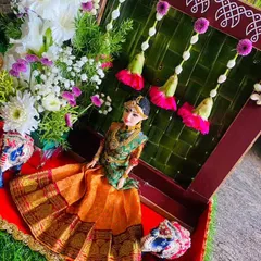 A close-up of a doll dressed in a beautiful orange and green half saree. I place these dolls in decorated boxes or platters, making them a unique focal point for puberty ceremonies or engagements.