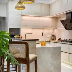 A kitchen should be both beautiful and highly functional. In this home, I designed a bright, open kitchen with a two-tiered breakfast counter and shaker-style cabinetry. The warm taupe and white palette, paired with finely veined marble, creates a clean, minimalist feel that is still warm and inviting.