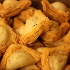 A close-up of our crowd-favorite Warkhi Samosas. Each one has dozens of flaky, paper-thin layers, filled with a choice of spiced mutton, chicken, or vegetables.