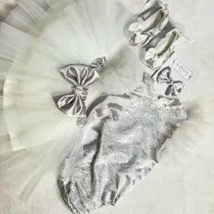 This newborn romper set in silver and white is pure elegance. It includes a lace-detailed romper, a tutu skirt, matching booties, and a bow headband.