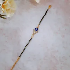 This mangalsutra bracelet features a Hamsa hand charm with an evil eye at its center, offering double the protection. The black beads and gold chain create a stylish and meaningful accessory.