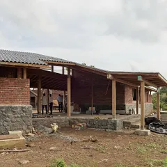This view shows the interplay of the sloping rooflines and the open verandas of the Kamshet farmhouse. The design breaks down the mass of the building, creating a series of interconnected indoor and outdoor living areas.