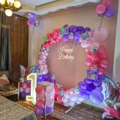 A full view of the butterfly-themed setup in a home, showing the ring backdrop, marquee number, and surrounding balloons.