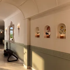 Arched niches with floral paintings and candles add a soft, artistic touch to the hallway, turning a simple passageway into a gallery of beautiful moments.