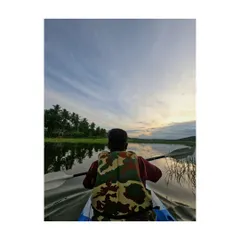 A kayaker paddles towards the setting sun, with the beautiful sky reflected on the water. A perfect moment of solitude and nature.