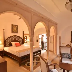 A Diwan-e-Khas room, where traditional decor and antique furniture create a unique atmosphere. The arched openings and windows connect the interior space to the historic bylanes of Chandni Chowk.