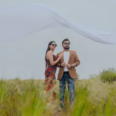 A dramatic shot in a grassy field in Goa, with a white cloth billowing in the wind. This photo has a cinematic and high-fashion feel.