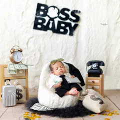 Here is the little boss in charge. This popular 'Boss Baby' setup includes a tiny suit, sunglasses, and a desk scene with money bags and a clock, making for a hilarious and memorable photo.