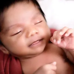 A close-up shot focusing on the pure, sleeping face of a newborn. These macro shots capture the details you'll want to remember forever, like their tiny lips and soft skin.