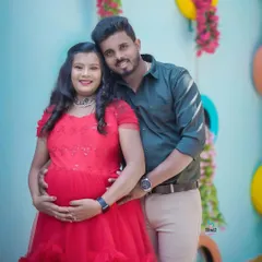 This couple chose a vibrant red gown for their indoor shoot. The colorful backdrop with hanging flowers adds a playful and happy touch to their portrait.