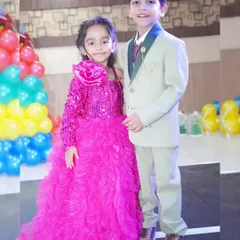 A brother and sister dressed in their party best, posing for a photo during a birthday event.