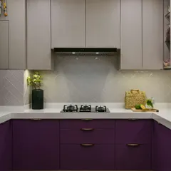 I transformed a closed-in kitchen into this bright and airy haven. Deep aubergine base cabinets with copper handles add a touch of luxury, while the white countertops and herringbone backsplash keep the space fresh and modern.