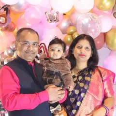 A family of three posing for a classic portrait in front of a pink and gold butterfly-themed balloon wall.