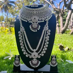 For a modern reception or sangeet look, this silver-plated CZ stone set with deep purple stones is a showstopper. It includes a choker, a multi-layered long necklace, and matching earrings, designed to catch the light and make you shine.