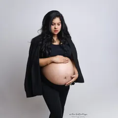 A quiet, contemplative pose. Draping the blazer over the shoulders adds a touch of high-fashion styling to this modern maternity look.