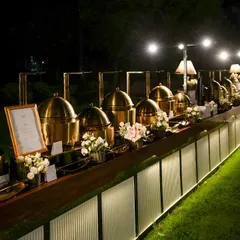 An elegant outdoor buffet setup for an evening corporate gala. Our illuminated counters and polished copper chafing dishes create a sophisticated ambiance while keeping main courses like our signature Hyderabadi Biryani at the perfect temperature.