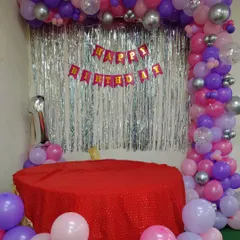 A simple balloon frame decoration for a first birthday, using purple, pink, and silver balloons around a cake table.