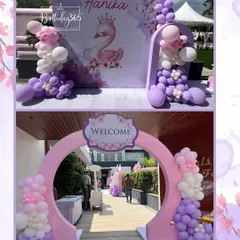 A dreamy entrance for a swan-themed birthday party. A circular pink archway adorned with balloons welcomes guests, leading to a beautiful photo backdrop featuring an elegant swan illustration and the birthday girl's name.