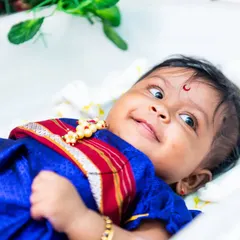 An adorable close-up of a baby girl in a traditional blue dress during her Naming Ceremony.
