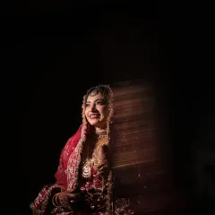 A candid moment of happiness. The bride's radiant smile is captured with creative lighting, creating a beautiful play of light and shadow that feels both artistic and genuine.