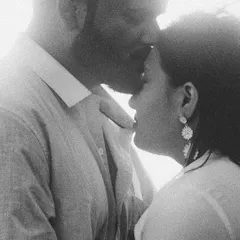 A tender, intimate moment frozen in time. This grainy black and white photograph captures the gentle emotion of a forehead kiss, focusing on the connection and love between the couple.