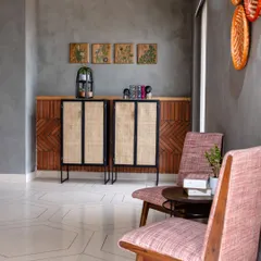 A cozy seating nook at Anthea Pharma, highlighting the blend of materials. The design features custom rattan cabinets, herringbone brick wainscoting, and patterned terrazzo flooring against a raw concrete wall.
