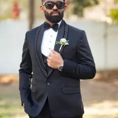 Looking sharp and ready to go. A classic portrait of the groom in his black tuxedo, looking effortlessly cool with his sunglasses on.