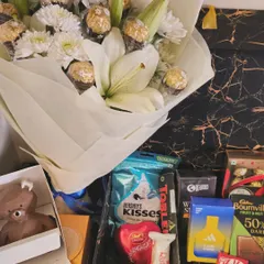 A luxurious birthday arrangement for men. This gift includes a bouquet of white lilies and Ferrero Rocher, paired with chocolates, a chocolate bear, and Adidas perfume.
