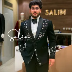 A client in my studio wearing a black tuxedo with intricate white and silver beaded floral patterns on the lapels and cuffs. It's a sophisticated take on the classic tuxedo for a wedding or reception.